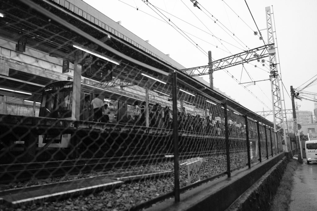 金網越しに駅のホームと電車をピント合わせして撮影した写真